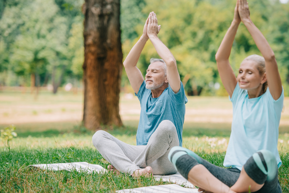 Senior couple doing yoga outdoors on 50plusses.com